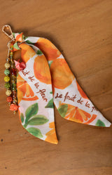 Decorative keychain with orange design on a wooden surface